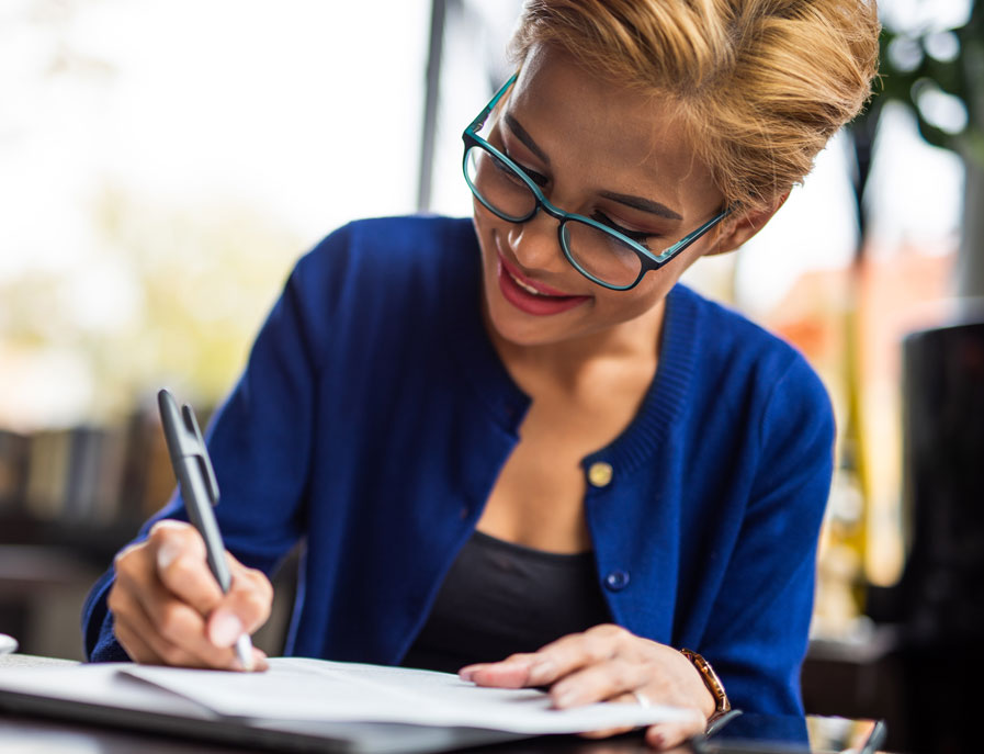 Photo of a young woman with a pen filling out a paper form.