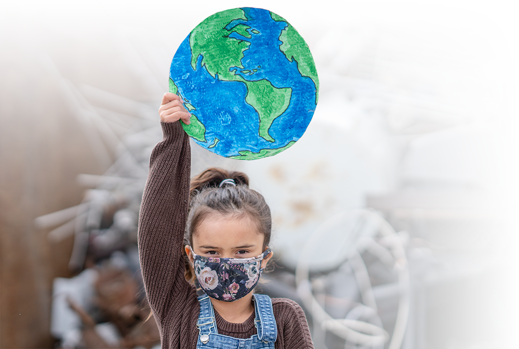 Photo of a masked young girl holding up a cutout drawing of Earth. Photo of a masked young girl holding up a cutout drawing of Earth.